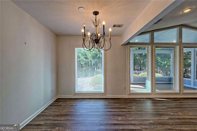 unfurnished dining area with dark wood-style flooring, visible vents, baseboards, and an inviting chandelier