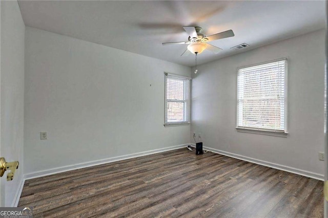 spare room featuring a ceiling fan, dark wood finished floors, visible vents, and baseboards