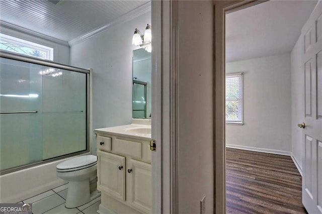 full bathroom featuring baseboards, bath / shower combo with glass door, toilet, ornamental molding, and vanity