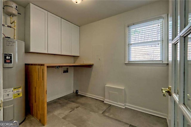 laundry area with light tile patterned flooring, electric water heater, washer hookup, baseboards, and cabinet space