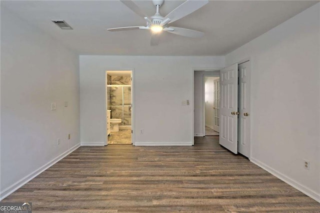 unfurnished bedroom featuring connected bathroom, visible vents, dark wood finished floors, and baseboards