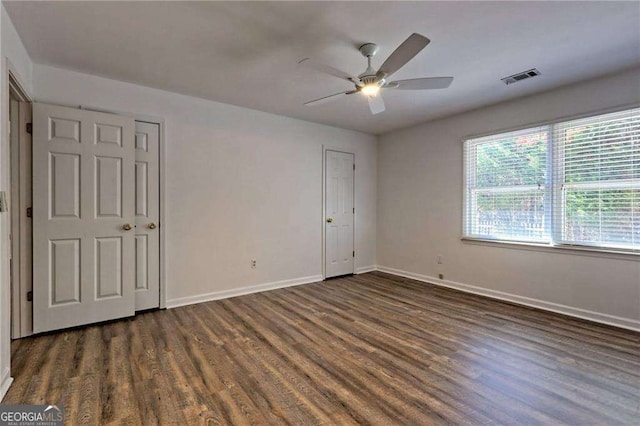 unfurnished bedroom with dark wood-type flooring, visible vents, ceiling fan, and baseboards