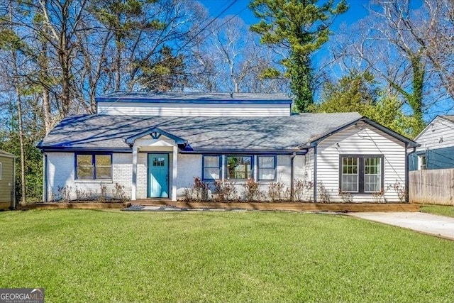 view of front of house with brick siding, a front yard, and fence