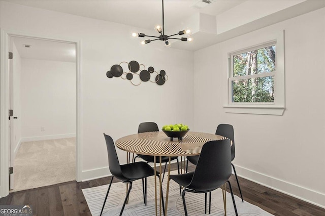 dining space featuring dark wood-style floors, an inviting chandelier, visible vents, and baseboards