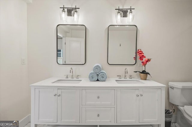 full bath featuring double vanity, a sink, and toilet