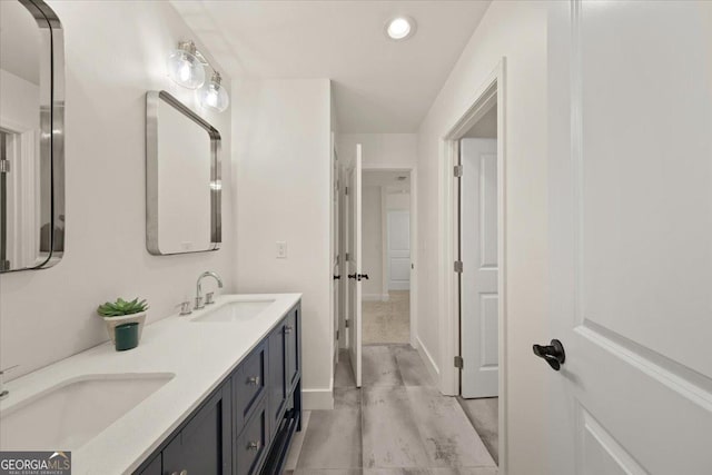 full bath with double vanity, a sink, and baseboards