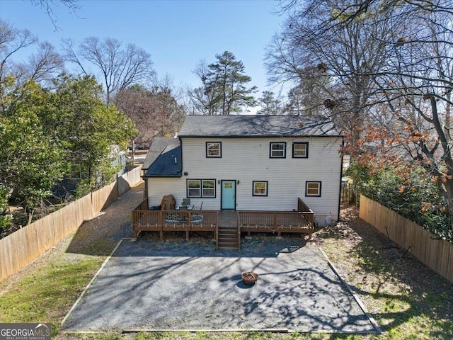 rear view of property with a fenced backyard and a deck