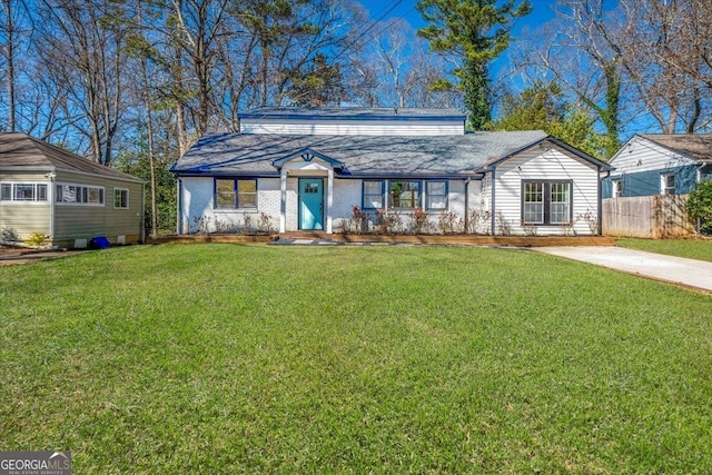 view of front facade featuring brick siding, fence, concrete driveway, and a front yard