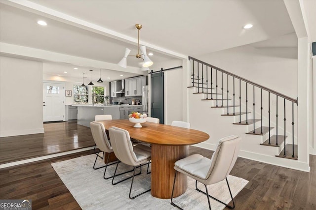 dining area with wood finished floors, baseboards, and a barn door