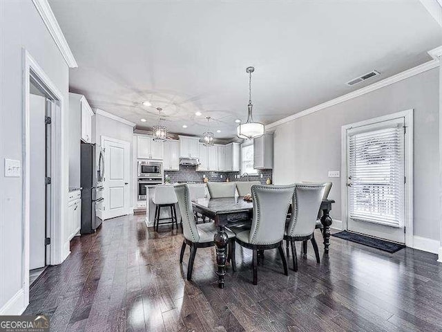 dining room featuring ornamental molding, dark wood-type flooring, and visible vents