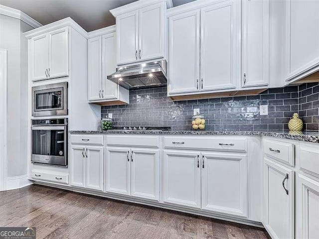 kitchen with stone counters, dark wood-style floors, appliances with stainless steel finishes, white cabinetry, and under cabinet range hood