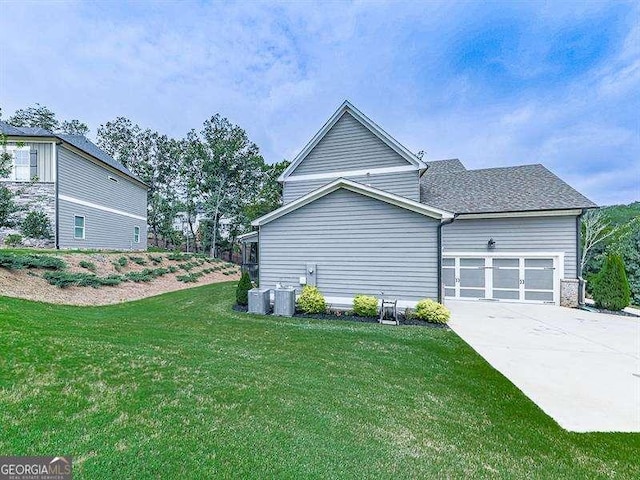 view of property exterior featuring driveway, an attached garage, a shingled roof, and a lawn