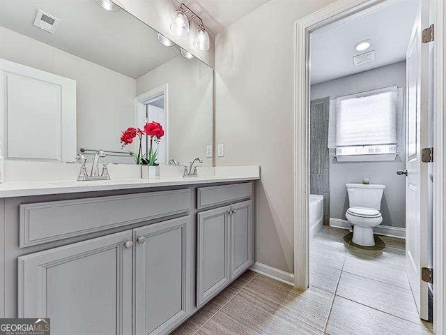 full bath with double vanity, baseboards, visible vents, toilet, and a sink