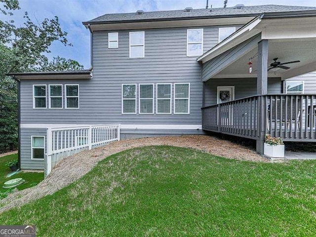 rear view of property featuring ceiling fan, a wooden deck, and a yard