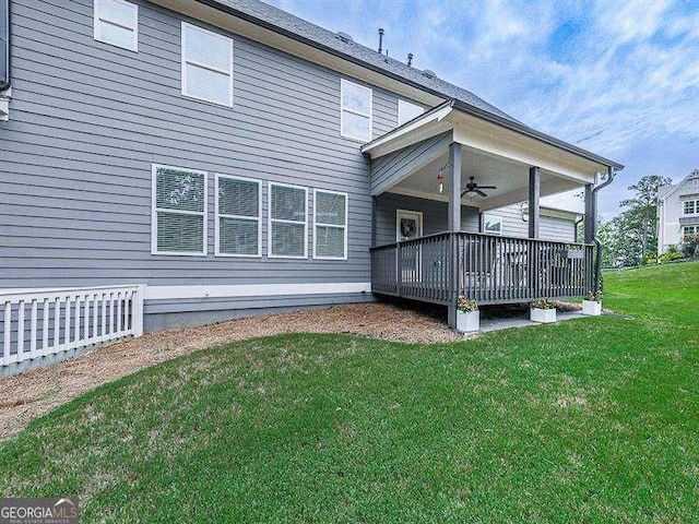 back of house featuring a ceiling fan, a yard, and a wooden deck