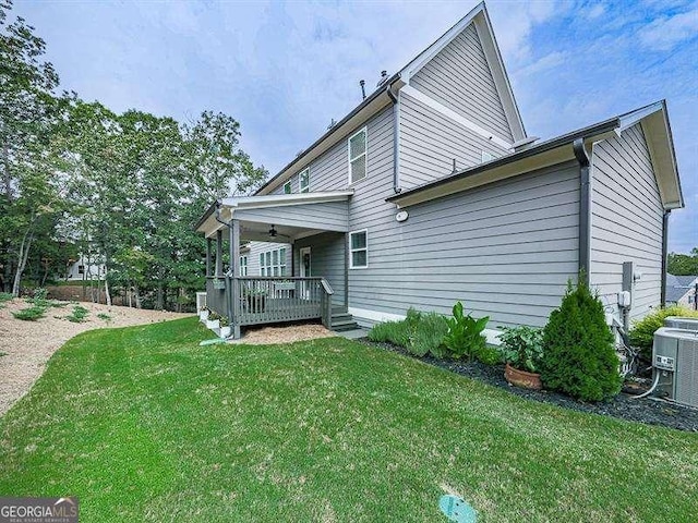 view of home's exterior featuring a lawn, cooling unit, and a wooden deck