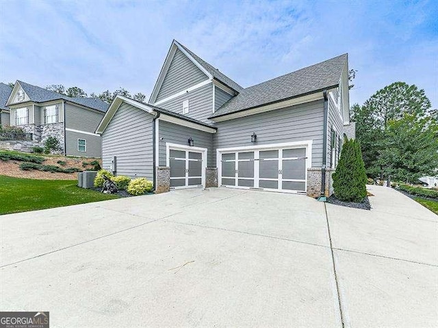 view of side of home with a garage, central AC, and driveway