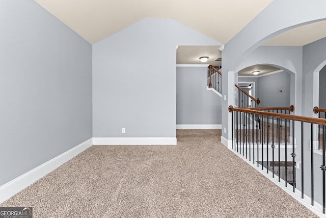 corridor featuring baseboards, arched walkways, lofted ceiling, stairway, and carpet floors