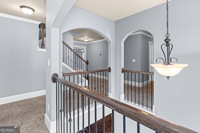 hall with crown molding, dark colored carpet, and baseboards