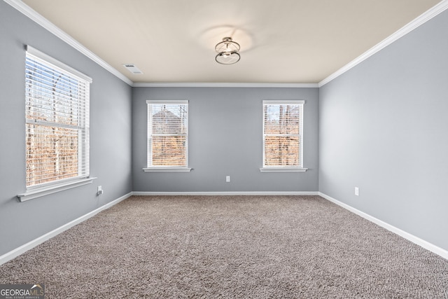 carpeted spare room featuring ornamental molding, plenty of natural light, visible vents, and baseboards