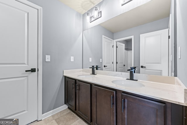 bathroom featuring double vanity, a sink, and baseboards