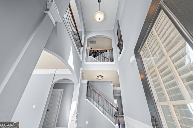 entrance foyer with visible vents, a towering ceiling, baseboards, and stairs