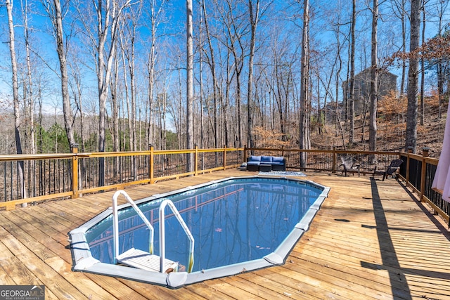 view of swimming pool with a wooded view and a wooden deck