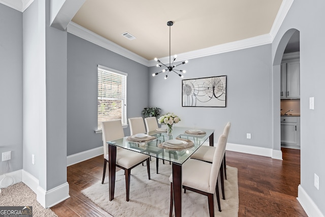 dining room featuring a chandelier, wood finished floors, visible vents, baseboards, and crown molding