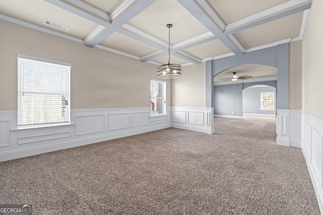 spare room featuring arched walkways, visible vents, beamed ceiling, and light carpet