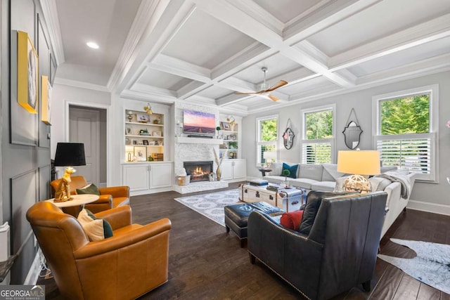 living area with a stone fireplace, built in shelves, coffered ceiling, dark wood-style floors, and beamed ceiling