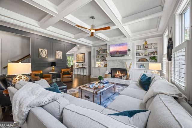 living room with built in shelves, dark wood-type flooring, a fireplace, coffered ceiling, and beamed ceiling