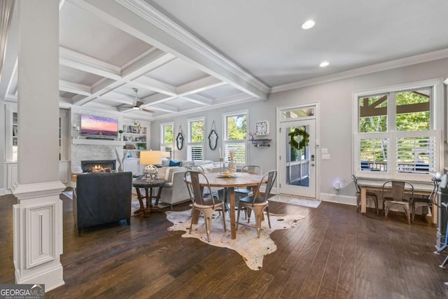 dining area with a healthy amount of sunlight, a warm lit fireplace, dark wood finished floors, and coffered ceiling