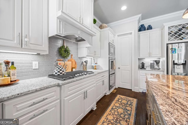 kitchen with ornamental molding, light stone countertops, stainless steel appliances, under cabinet range hood, and white cabinetry