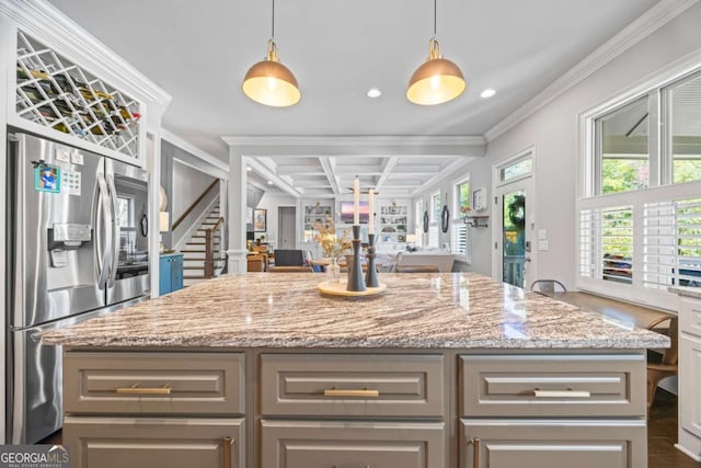 kitchen featuring open floor plan, light stone counters, stainless steel refrigerator with ice dispenser, and a healthy amount of sunlight