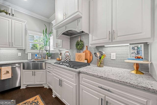 kitchen with stainless steel appliances, white cabinets, a sink, and ornamental molding