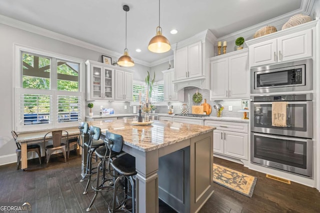 kitchen featuring stainless steel appliances, glass insert cabinets, white cabinetry, and light stone countertops