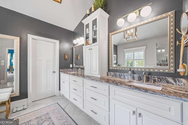 full bath featuring lofted ceiling, marble finish floor, a sink, and double vanity