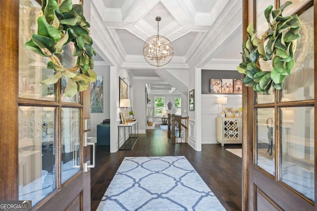 foyer featuring dark wood-style floors, a notable chandelier, ornamental molding, coffered ceiling, and beamed ceiling