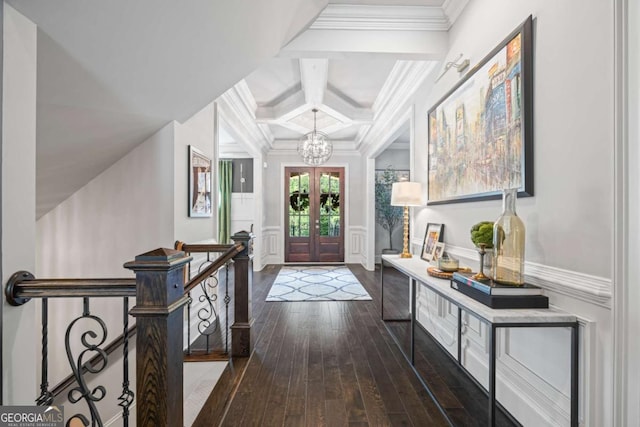 entrance foyer featuring coffered ceiling, dark wood finished floors, ornamental molding, a chandelier, and beam ceiling