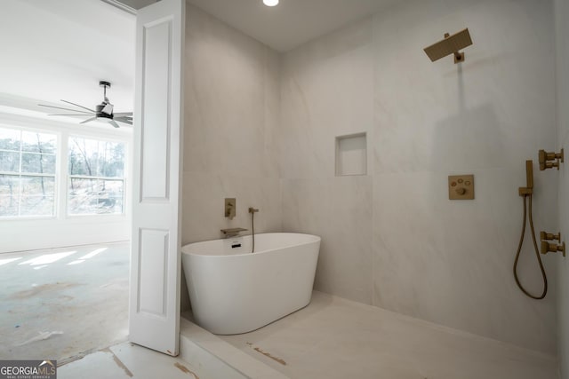 full bath featuring a ceiling fan, a soaking tub, and tile walls