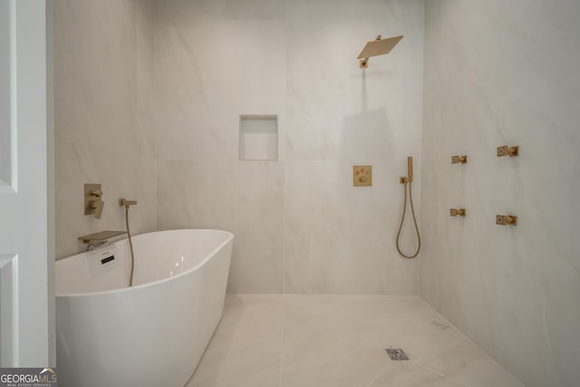 full bathroom featuring tile patterned flooring, a freestanding bath, and tile walls