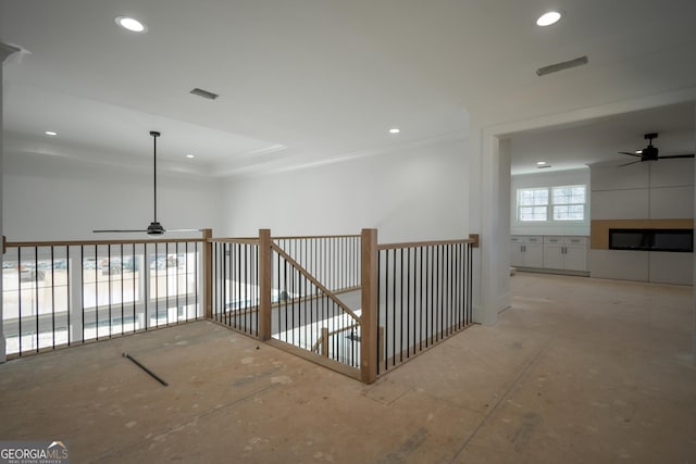 hallway with an upstairs landing, visible vents, a raised ceiling, and recessed lighting