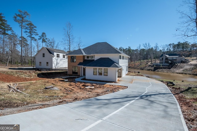 view of front facade with concrete driveway and roof with shingles