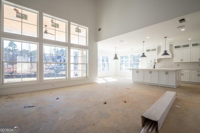 unfurnished living room featuring a towering ceiling, a sink, and visible vents