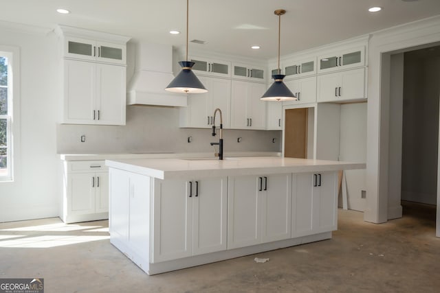 kitchen featuring glass insert cabinets, a center island with sink, custom exhaust hood, and light countertops