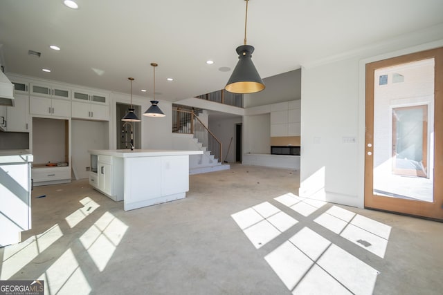 kitchen with white cabinets, a kitchen island, glass insert cabinets, decorative light fixtures, and light countertops