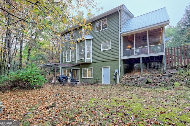 back of property with metal roof and a sunroom