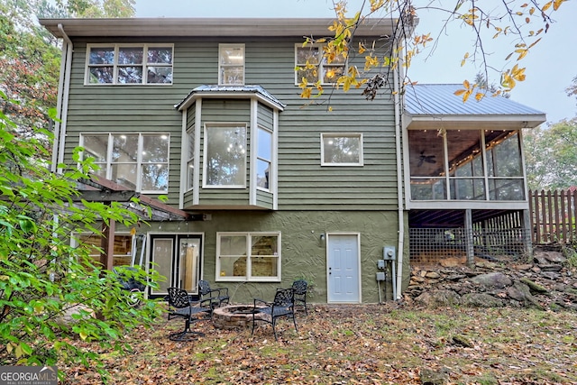 back of property with a fire pit, metal roof, a sunroom, and stucco siding