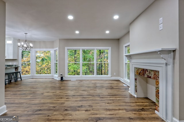 unfurnished living room with recessed lighting, plenty of natural light, and an inviting chandelier