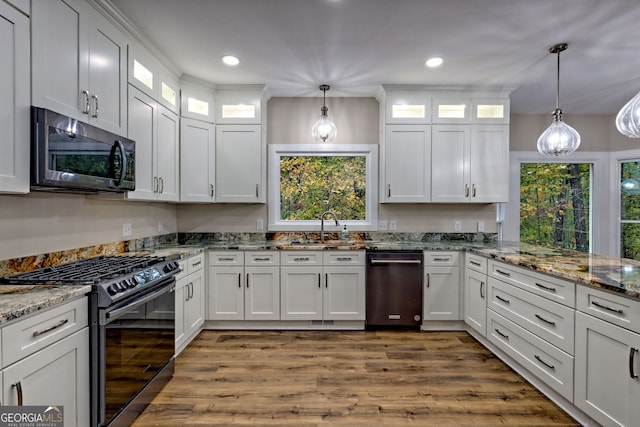 kitchen featuring white cabinets, light stone counters, glass insert cabinets, hanging light fixtures, and stainless steel appliances